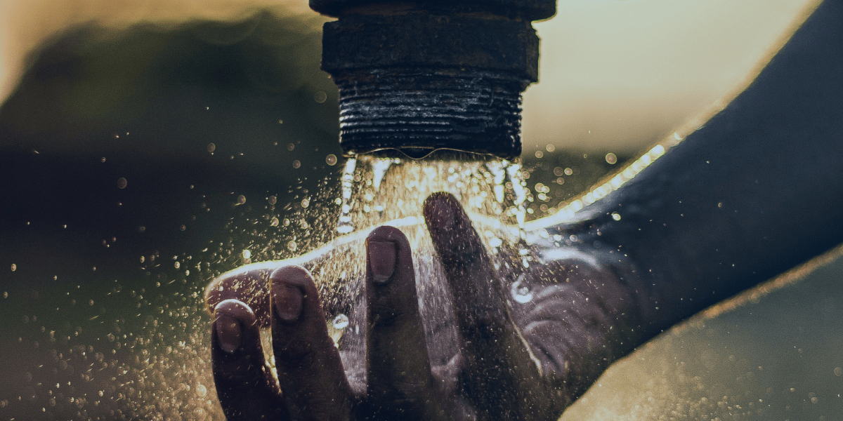 mãos com agua caindo de um cano