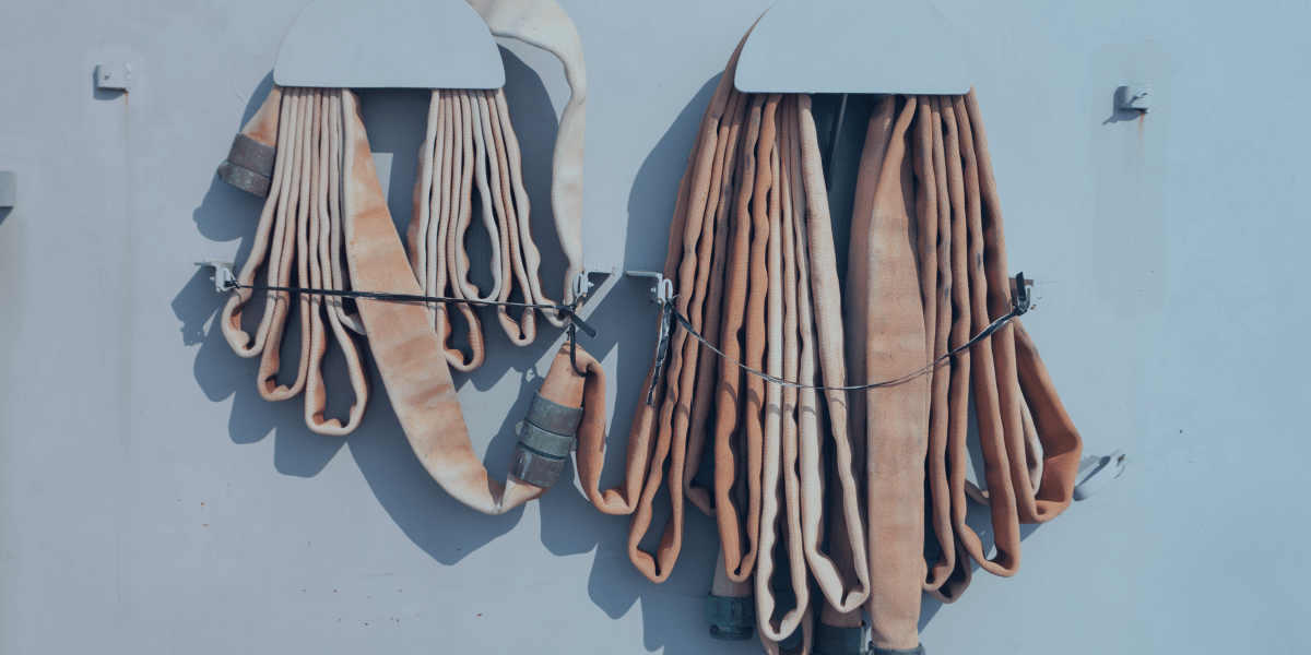 mangueiras de incêndio de cor clara, penduradas em uma parede